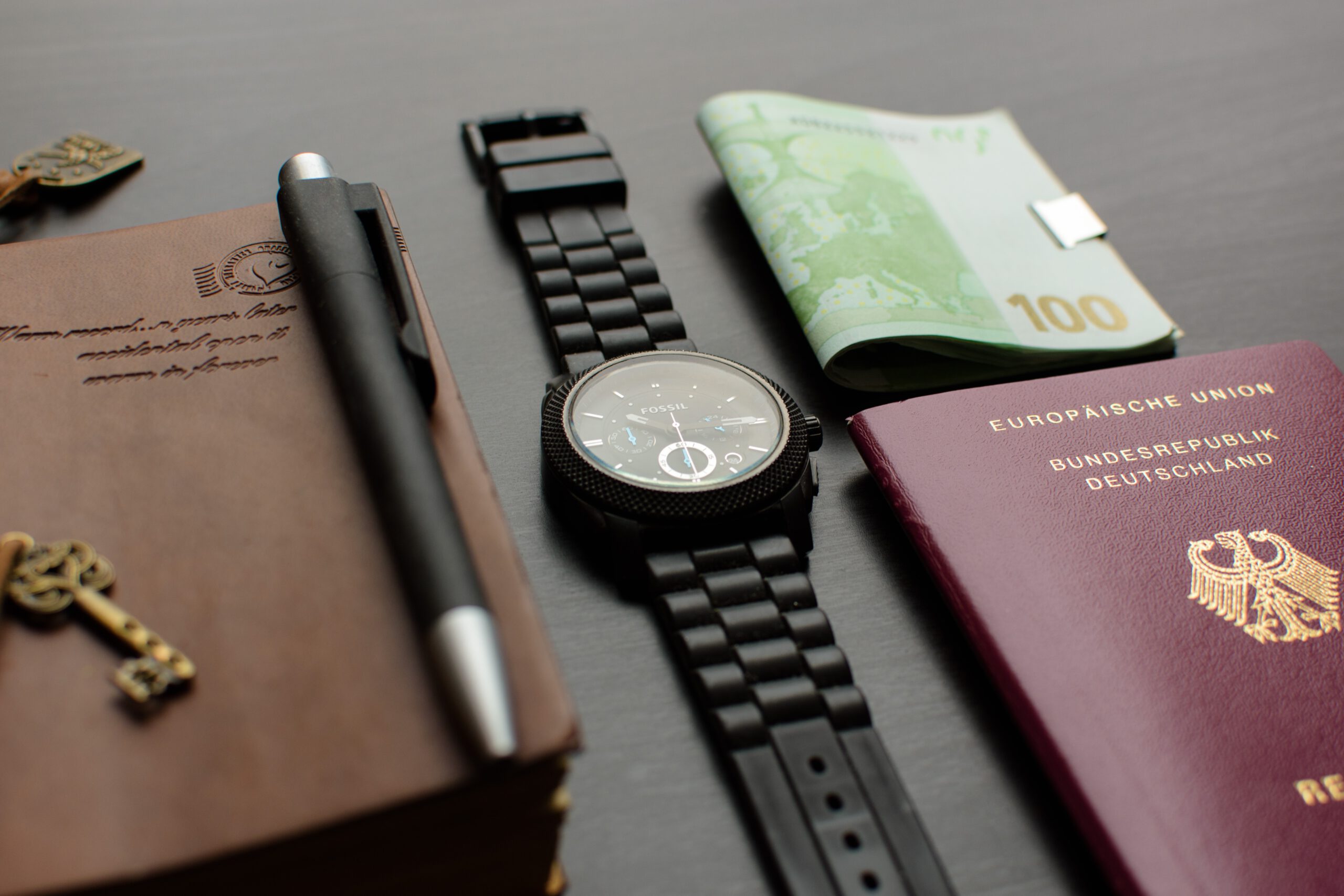 Paszport, zegarek na pasku i dokuemnty leżące na stole